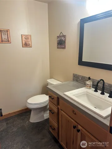 a bathroom with a granite countertop toilet sink and mirror