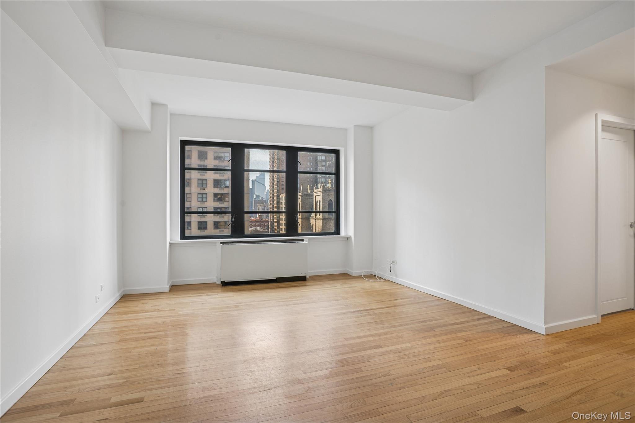 43 West 61st Street, Unit 12F Manhattan, NY 10023 - Photo 4 of 14 wooden floor in an empty room with a window