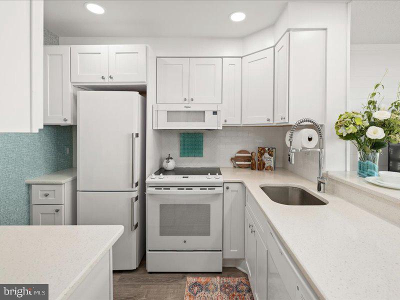 409 Annapolis House Road, Unit 409N Bethany Beach, DE 19930 - Photo 11 of 75 a kitchen with white cabinets and white appliances
