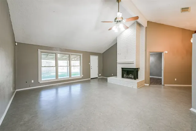 an empty room with windows and fireplace