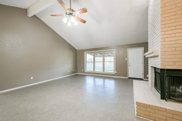 an empty room with windows and fireplace