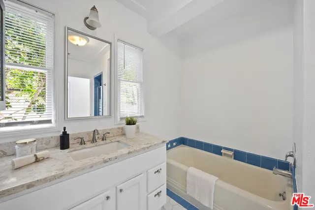 a bathroom with a granite countertop sink mirror and a bathtub