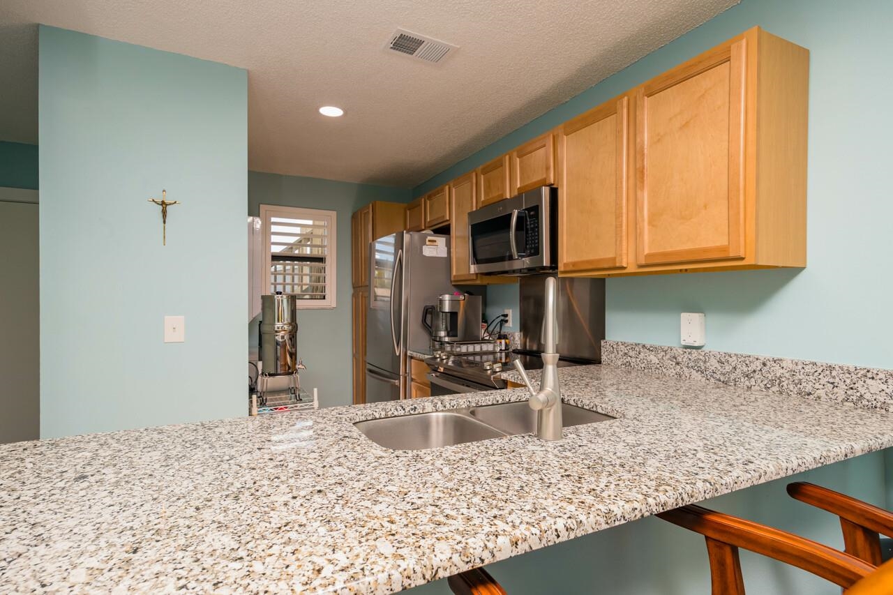 650 West Pope Road, Unit 240 St. Augustine, FL 32080 - Photo 11 of 35 a kitchen with granite countertop a sink a stove and a wooden cabinets