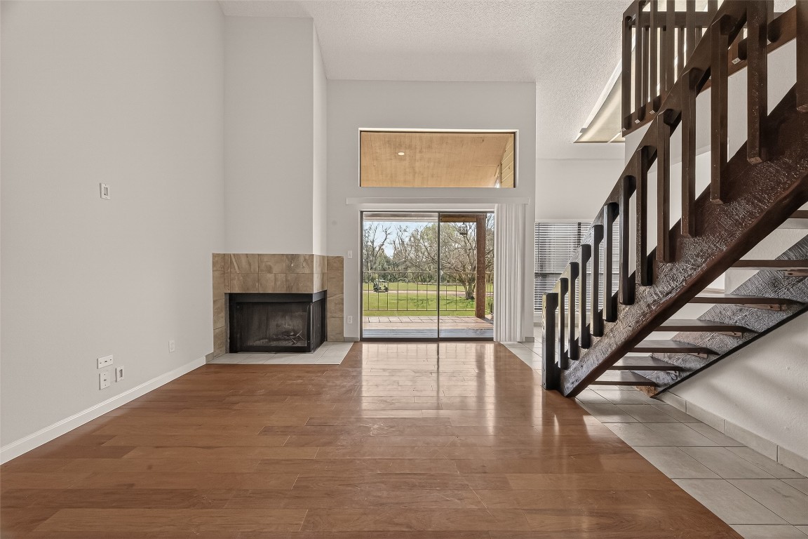an empty room with wooden floor fireplace and windows