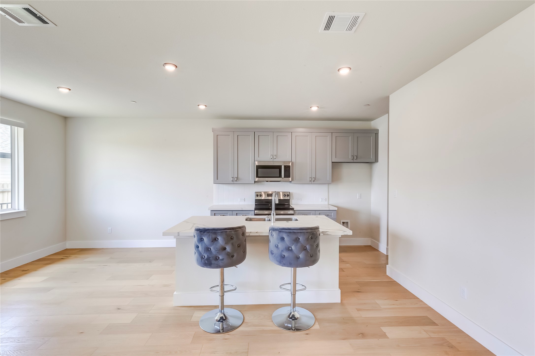 2600 Gattis School Road, Unit 401 Round Rock, TX 78664 - Photo 12 of 29 Kitchen featuring a kitchen breakfast bar, an island with sink, stainless steel appliances, light wood-type flooring, and gray cabinets