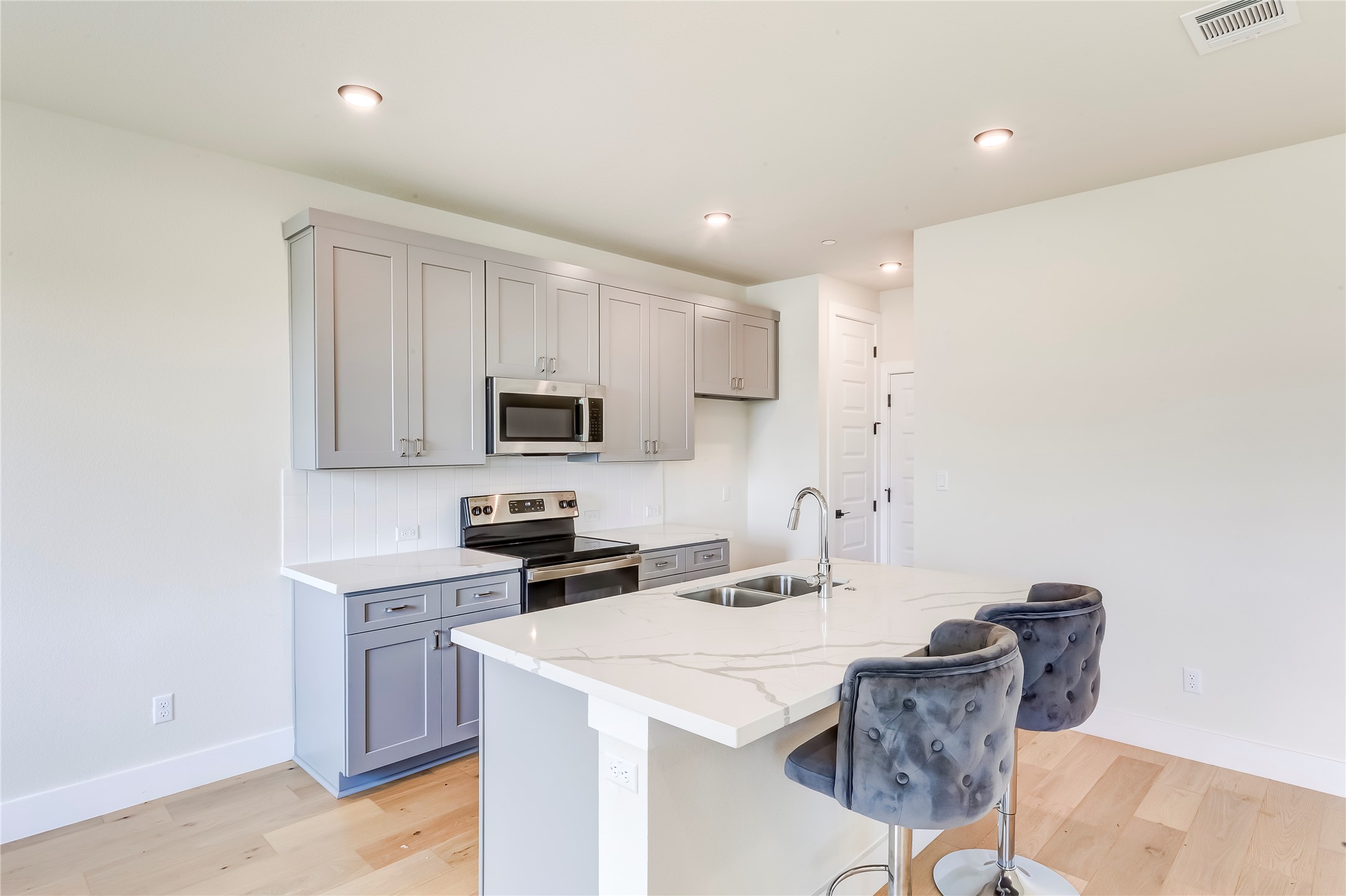 2600 Gattis School Road, Unit 401 Round Rock, TX 78664 - Photo 13 of 29 Kitchen featuring gray cabinetry, stainless steel appliances, a breakfast bar, light wood-style floors, and recessed lighting