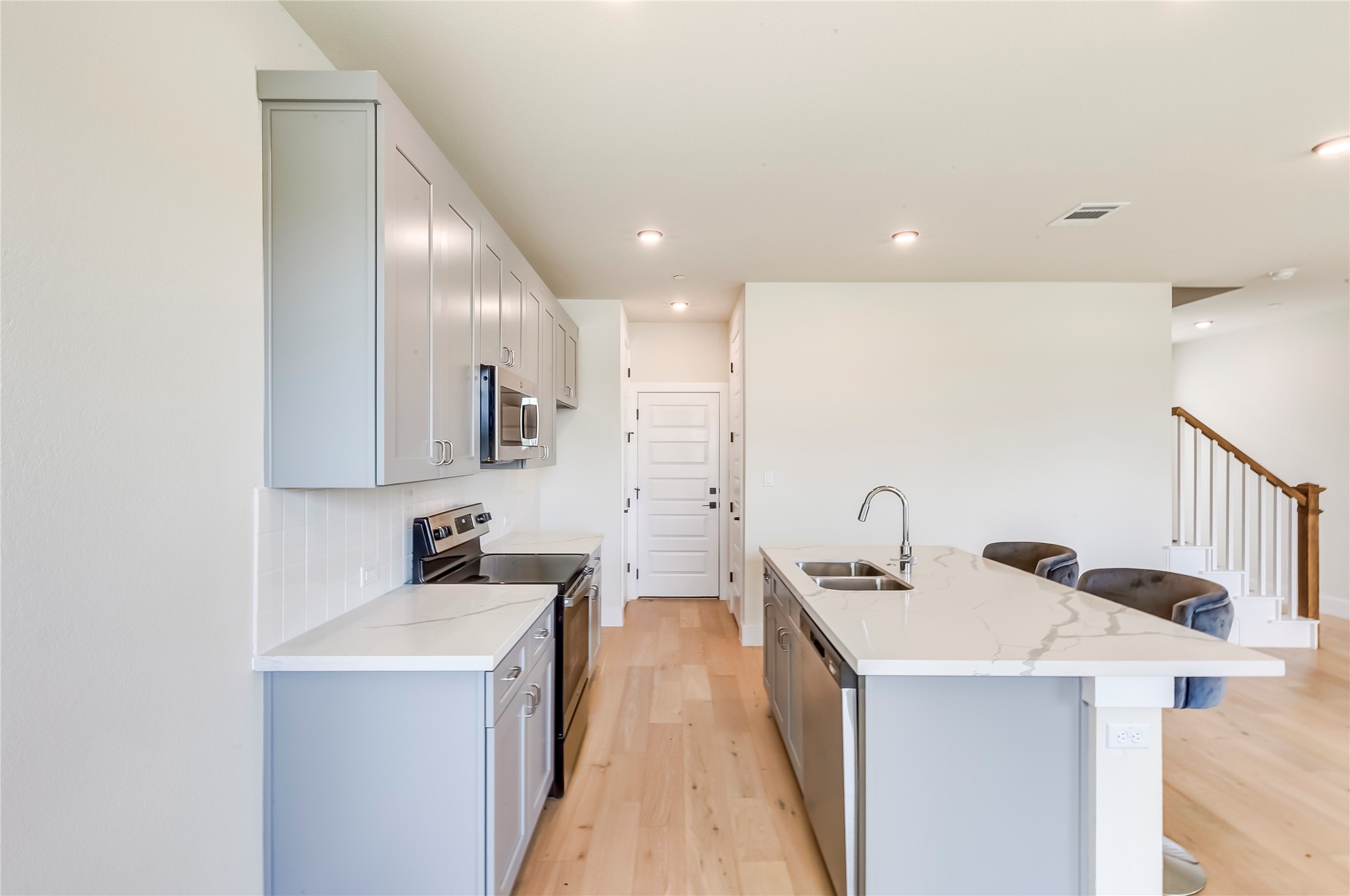 2600 Gattis School Road, Unit 401 Round Rock, TX 78664 - Photo 14 of 29 Kitchen featuring gray cabinetry, stainless steel appliances, a breakfast bar, a kitchen island with sink, and light wood-type flooring