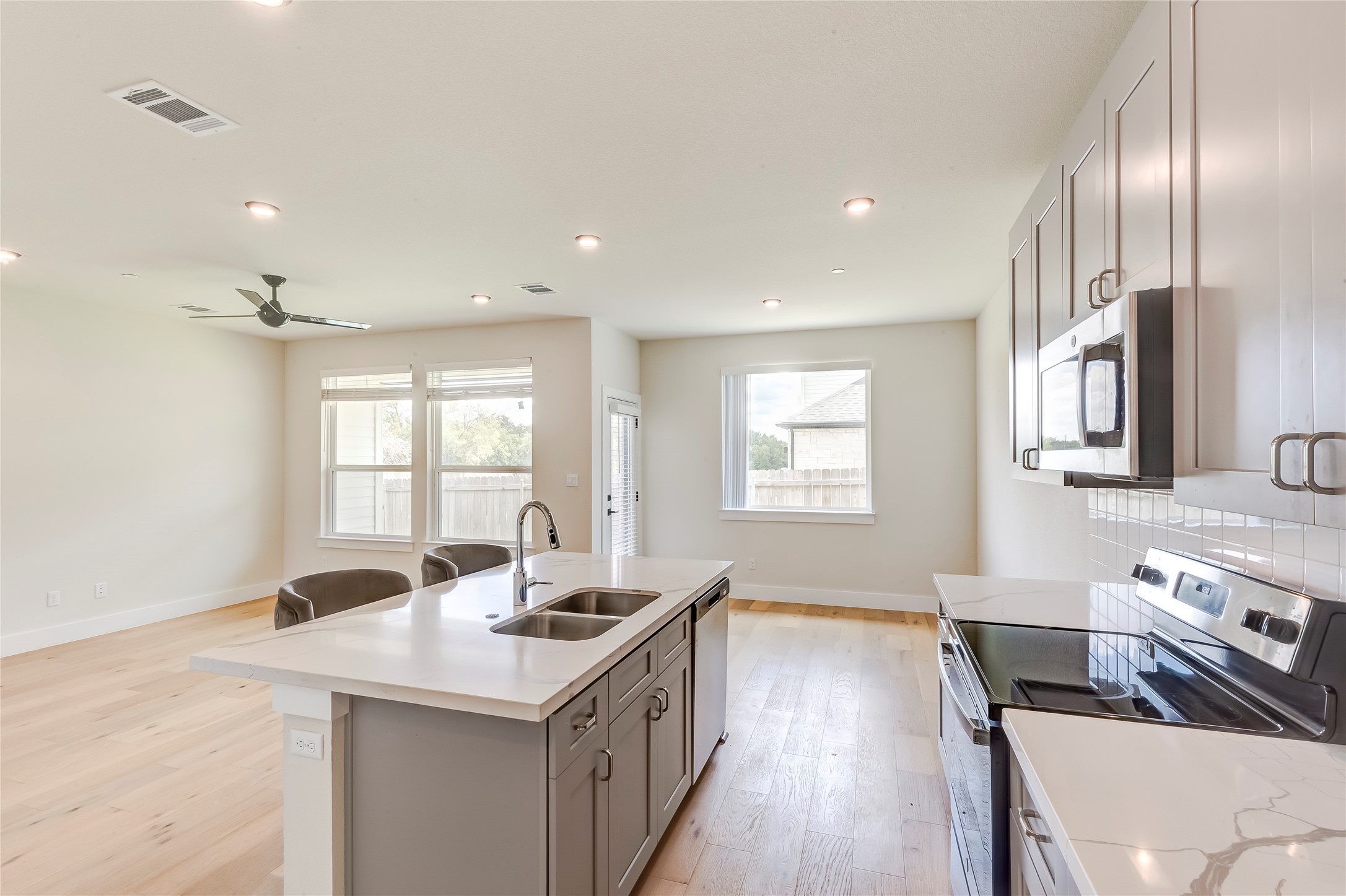 2600 Gattis School Road, Unit 401 Round Rock, TX 78664 - Photo 15 of 29 Kitchen with stainless steel appliances, light wood-type flooring, a kitchen island with sink, gray cabinets, and plenty of natural light