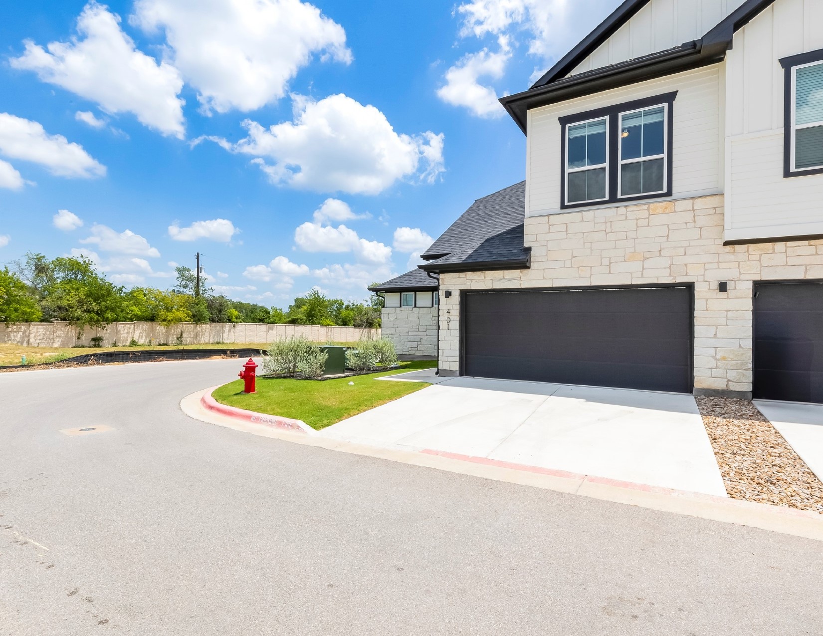 2600 Gattis School Road, Unit 401 Round Rock, TX 78664 - Photo 4 of 29 View of property exterior with stone siding, concrete driveway, board and batten siding, and a garage