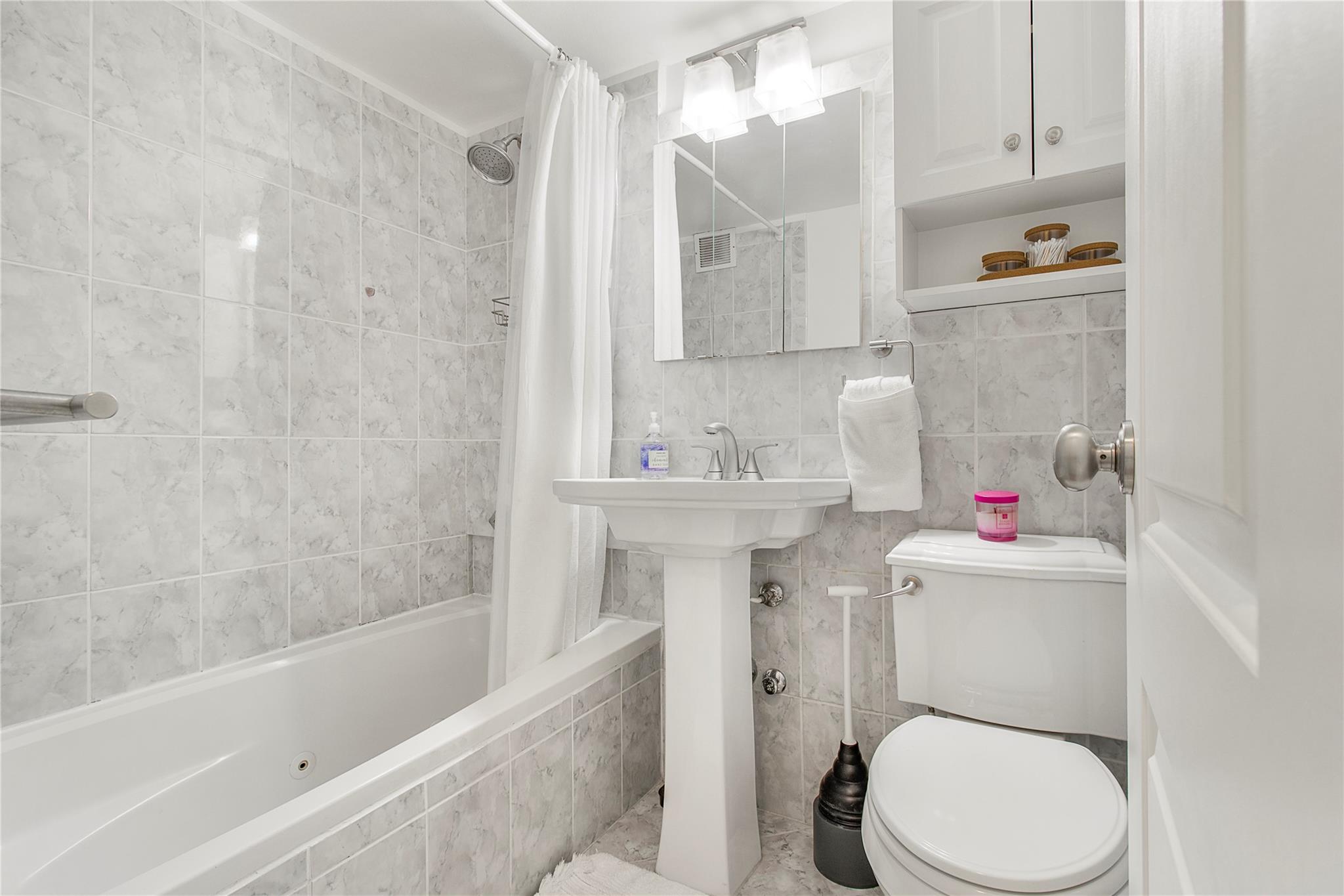 210 East 63rd Street, Unit 10E Manhattan, NY 10065 - Photo 14 of 15 Bathroom featuring tiled shower / bath combo, tile walls, and toilet