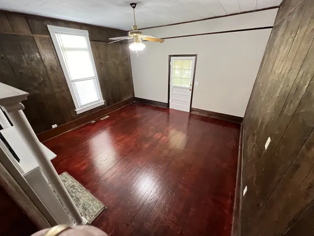 a view of an empty room with wooden floor and a window