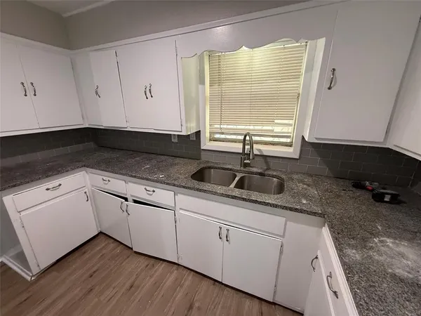 a kitchen with granite countertop white cabinets and a sink
