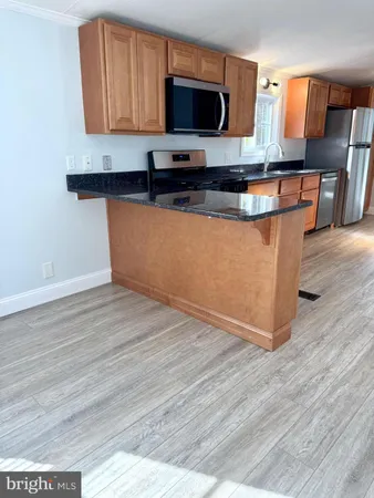 a kitchen with stainless steel appliances granite countertop a sink a stove top oven a counter space and wooden floor
