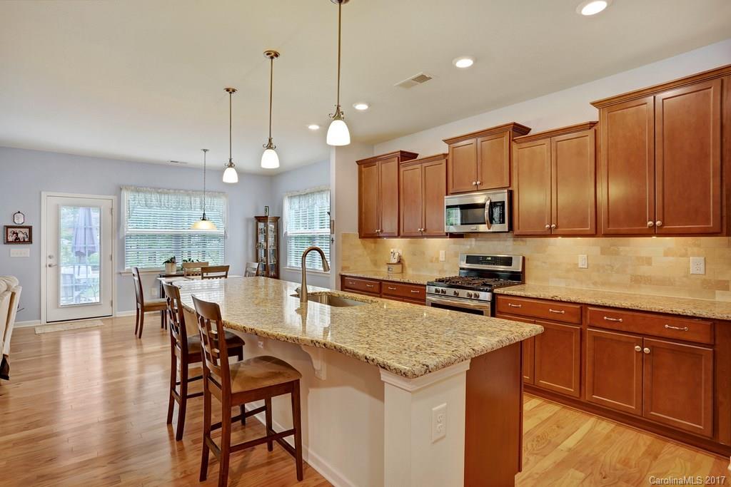 4135 Perth Road, Unit 374 Indian Land, SC 29707 - Photo 12 of 24 a kitchen with kitchen island granite countertop wooden cabinets and white appliances