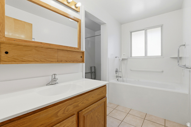 2348 North 770 West Clinton, UT 84015 - Photo 11 of 25 Bathroom featuring a vanity with a white countertop and integral sink, a large wood-framed mirror, and a built-in bathtub with an overhead shower fixture