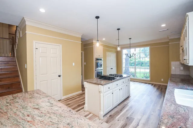 a kitchen with granite countertop a stove a sink and a wooden floor