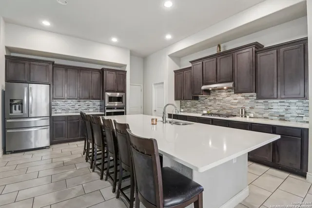 a kitchen with kitchen island granite countertop a sink cabinets and stainless steel appliances