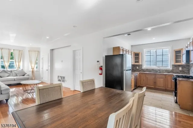 a kitchen with stainless steel appliances granite countertop a refrigerator a sink a stove a dining table and chairs