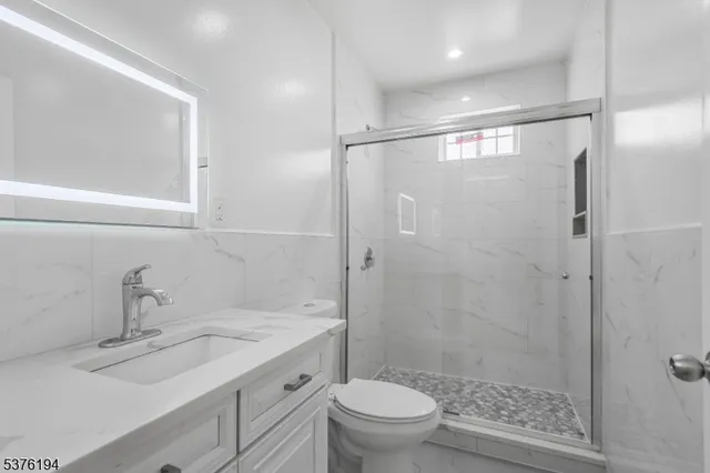 a bathroom with a shower sink vanity mirror and toilet
