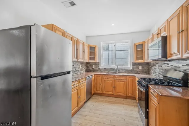 a kitchen with stainless steel appliances granite countertop a refrigerator a sink and dishwasher