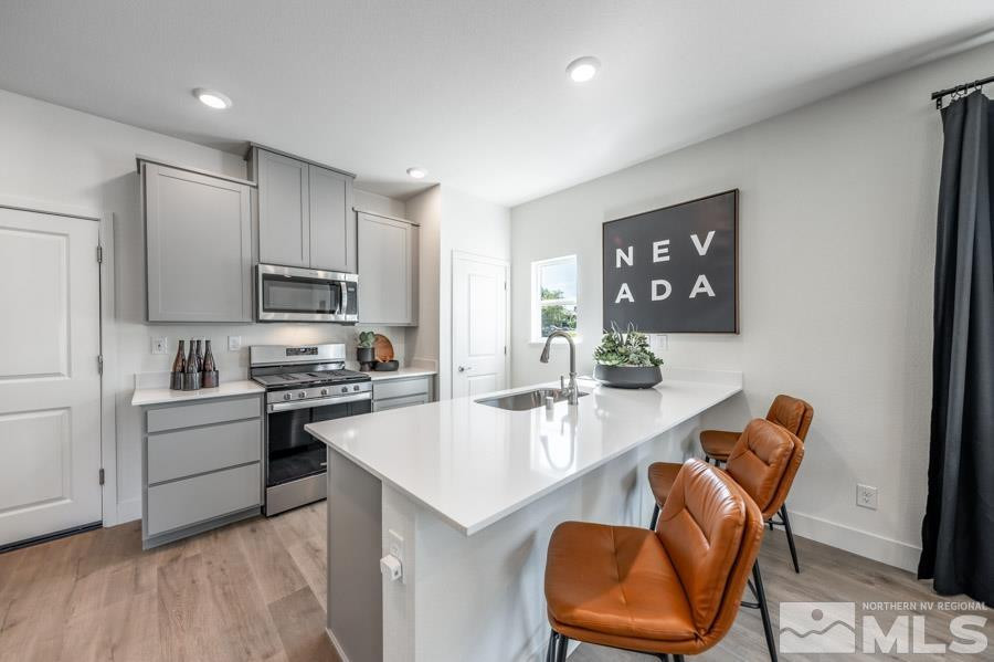 1621 Switchback Street, Unit LOT #25 Reno, NV 89523 - Photo 5 of 19 a kitchen with stainless steel appliances granite countertop a stove top oven a sink dishwasher and a refrigerator with wooden floor
