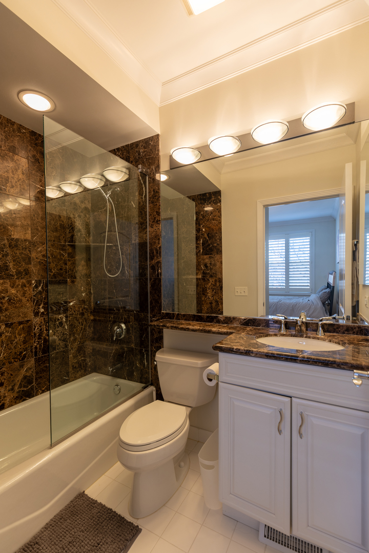 1125 West Monroe Street Chicago, IL 60607 - Photo 31 of 49 a bathroom with a granite countertop sink a toilet a mirror and bathtub
