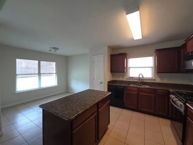 a kitchen with stainless steel appliances granite countertop stove top oven a sink and dishwasher next to a window