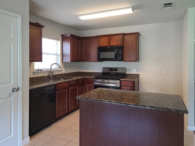 a kitchen with stainless steel appliances granite countertop a stove a sink and a microwave