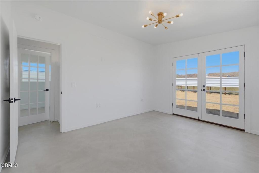 61714 Commercial Street Joshua Tree, CA 92252 - Photo 15 of 42 an empty room with chandelier fan and windows