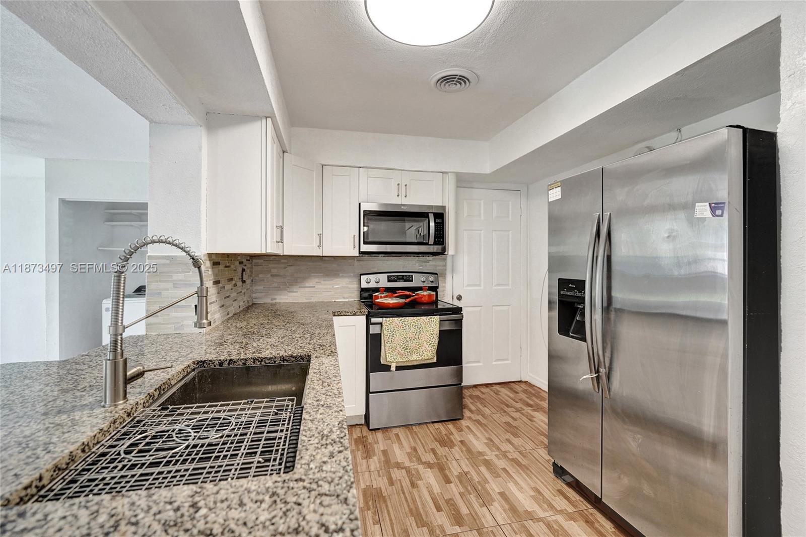 3330 Taft Street Hollywood, FL 33021 - Photo 26 of 70 a kitchen with granite countertop a refrigerator and a stove top oven
