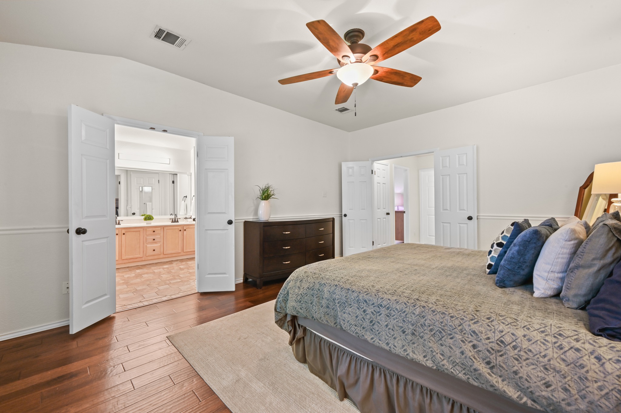 1409 Knoll Ridge Drive Cedar Park, TX 78613 - Photo 16 of 30 Rich hardwood floors complement this spacious bedroom, leading to an adjoining bath with double vanities.