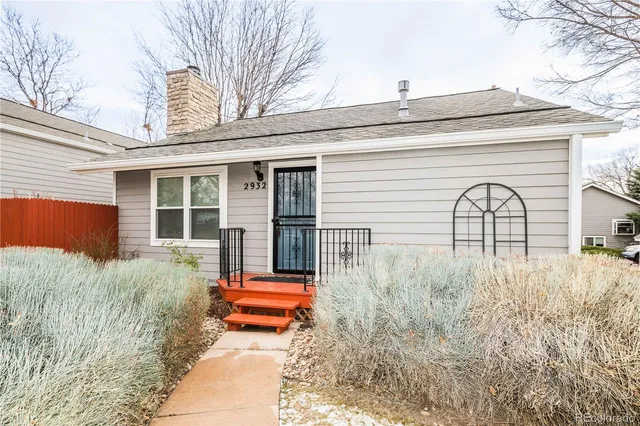 a backyard of a house with large trees and wooden fence