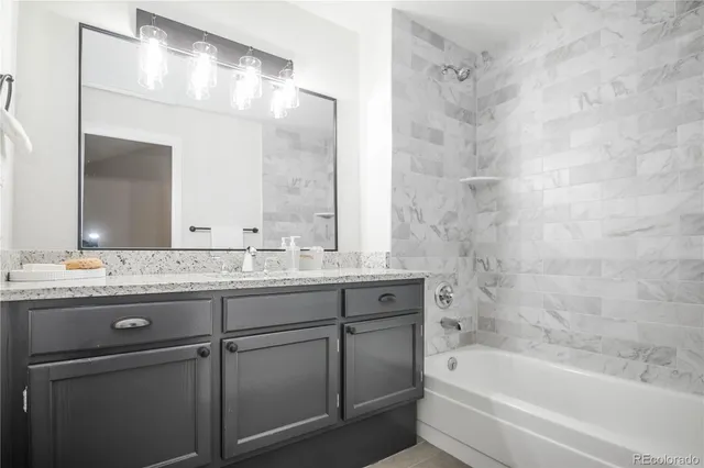 a bathroom with a granite countertop bathtub sink vanity and mirror