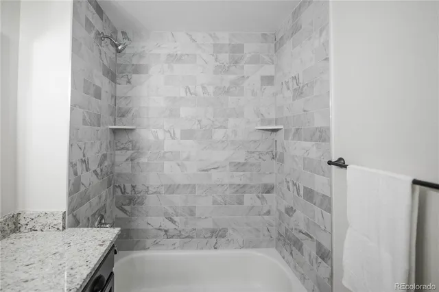 a bathroom with a granite countertop shower and a sink