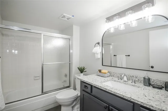 a bathroom with a granite countertop sink toilet and shower