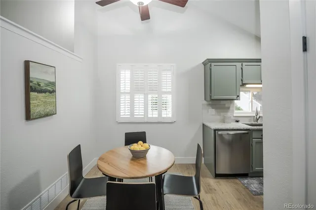 a kitchen with stainless steel appliances granite countertop a stove a refrigerator a sink a dining table and chairs with wooden floor