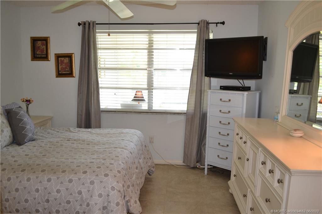 1969 Southwest Palm City Road, Unit G Stuart, FL 34994 - Photo 24 of 76 a bedroom with a bed and a flat tv screen on dresser