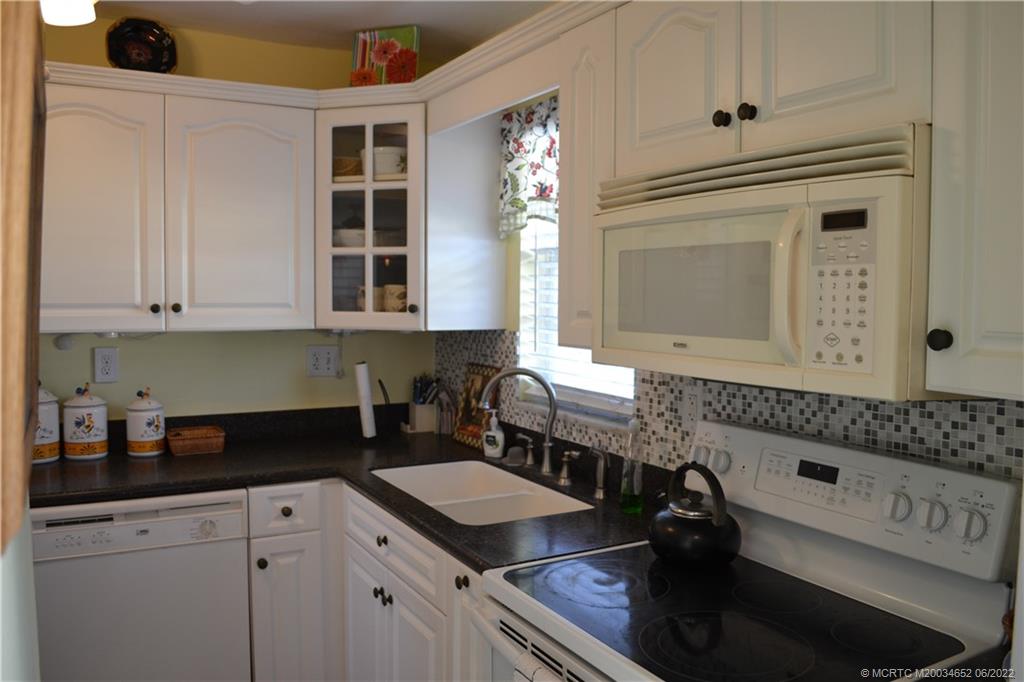 1969 Southwest Palm City Road, Unit G Stuart, FL 34994 - Photo 8 of 76 a kitchen with granite countertop a sink a stove and cabinets