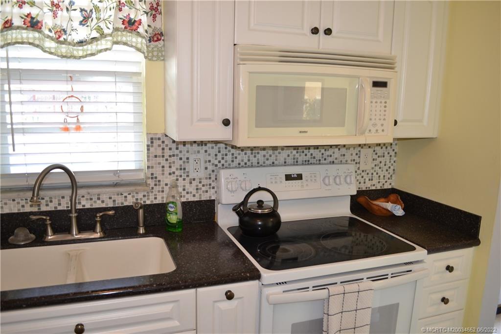 1969 Southwest Palm City Road, Unit G Stuart, FL 34994 - Photo 10 of 76 a close view of a stove a microwave a sink and dishwasher with wooden floor
