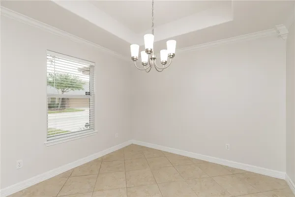 a view of empty room with window and chandelier