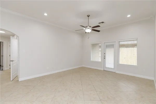 an empty room with a chandelier fan and windows