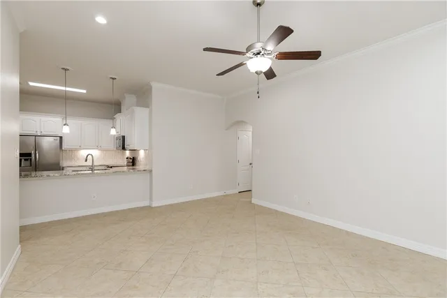an empty room with a kitchen and a chandelier fan