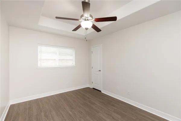 an empty room with wooden floor ceiling fan and window