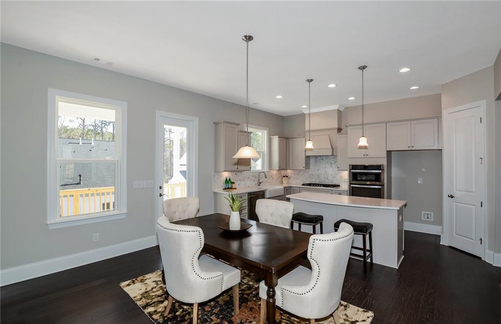 4316 Azalea Rdg Way Hoschton, GA 30548 - Photo 13 of 36 a kitchen with a dining table chairs microwave and cabinets