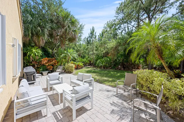 a view of a backyard with couches table and chairs and garden