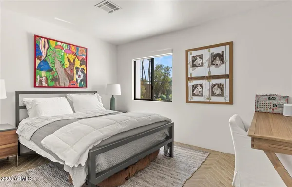 a bedroom with a bed and painting on the wall