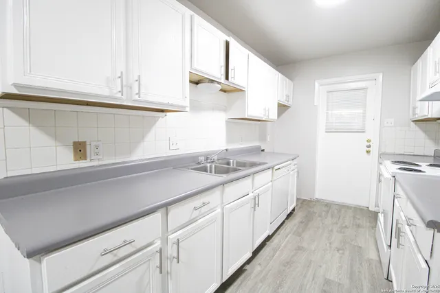 a kitchen with granite countertop a sink stove and cabinets