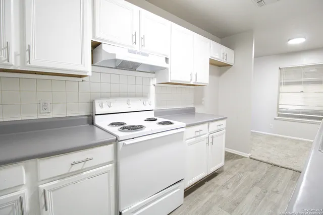 a kitchen with a stove cabinets and wooden floor