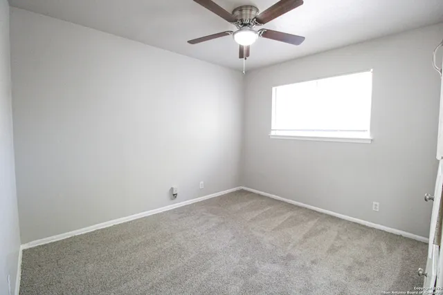 an empty room with a window and a fan