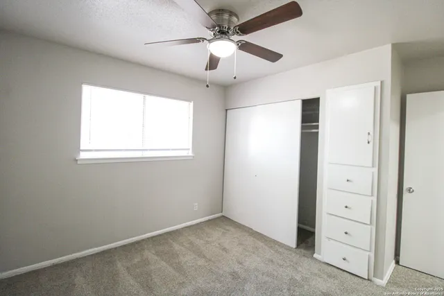 an empty room with windows and fan